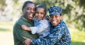 Two parents hug a child and smile to the camera