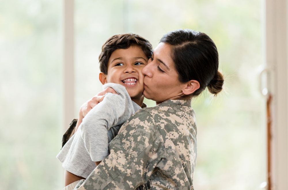 mom, a military person, and kid hugging 